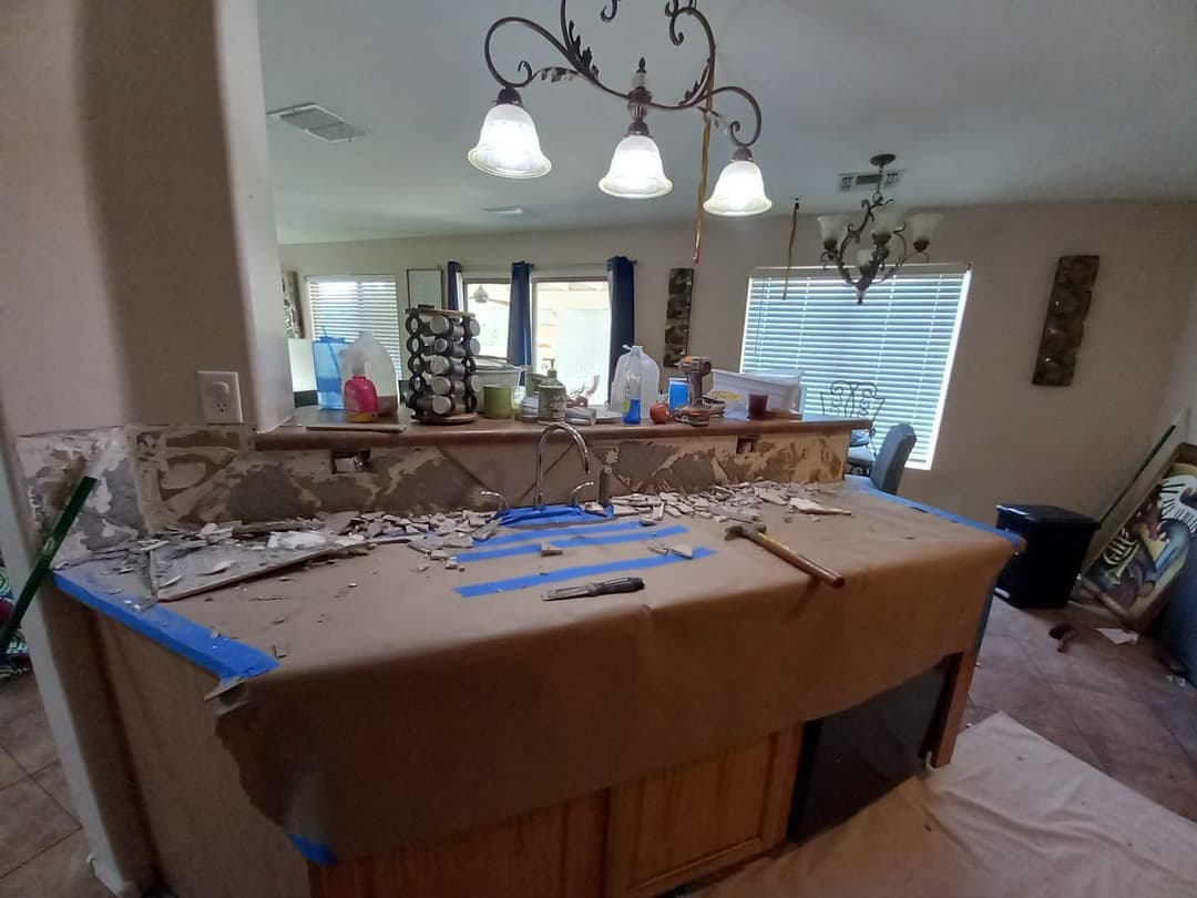 Renovation progress in a kitchen with exposed countertops and tools on a drop cloth.