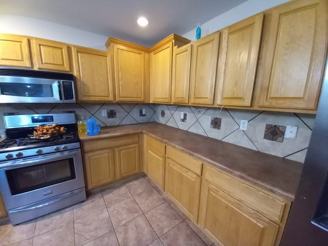 Modern kitchen with wooden cabinets, stainless steel appliances, and tiled backsplash.