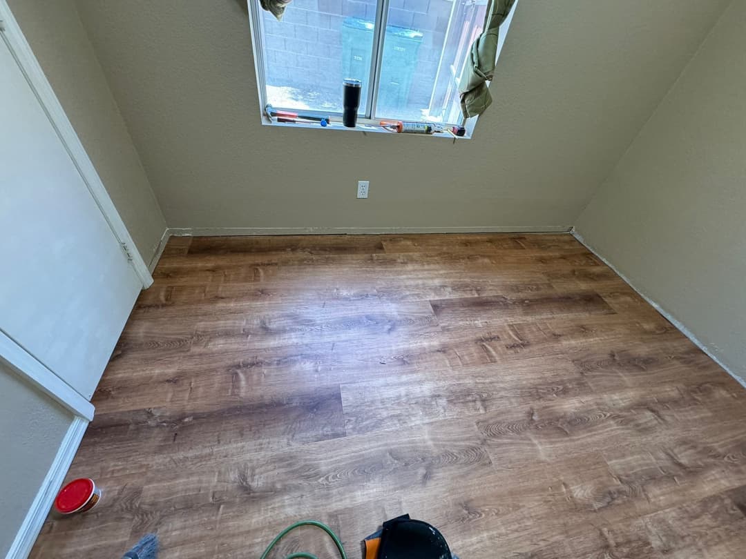 empty room with light brown laminate flooring and large window, awaiting furnishings and decor