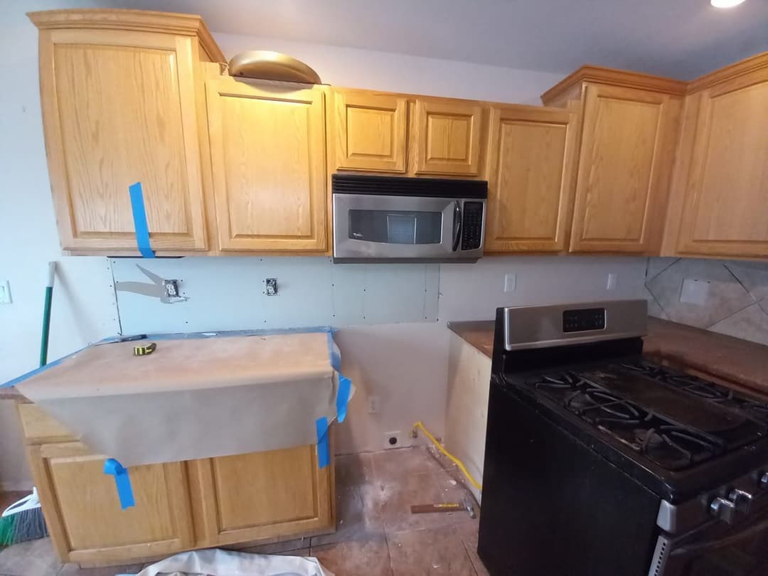 Renovated kitchen with wooden cabinets, stainless steel appliances, and exposed wall.