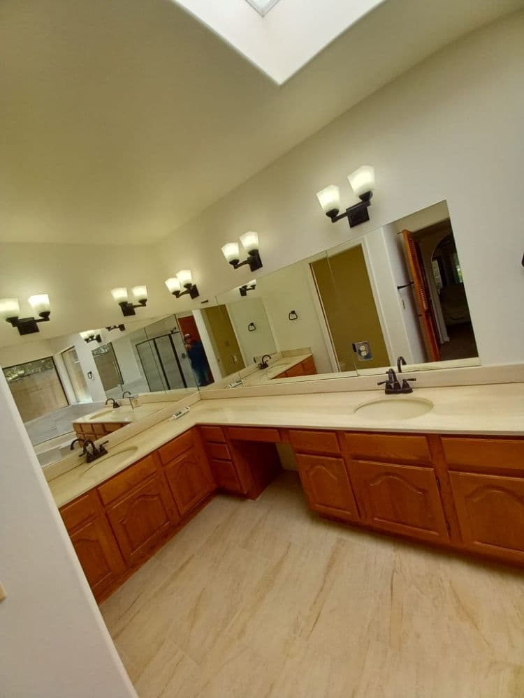 Spacious bathroom with dual sinks, mirrors, and modern light fixtures.
