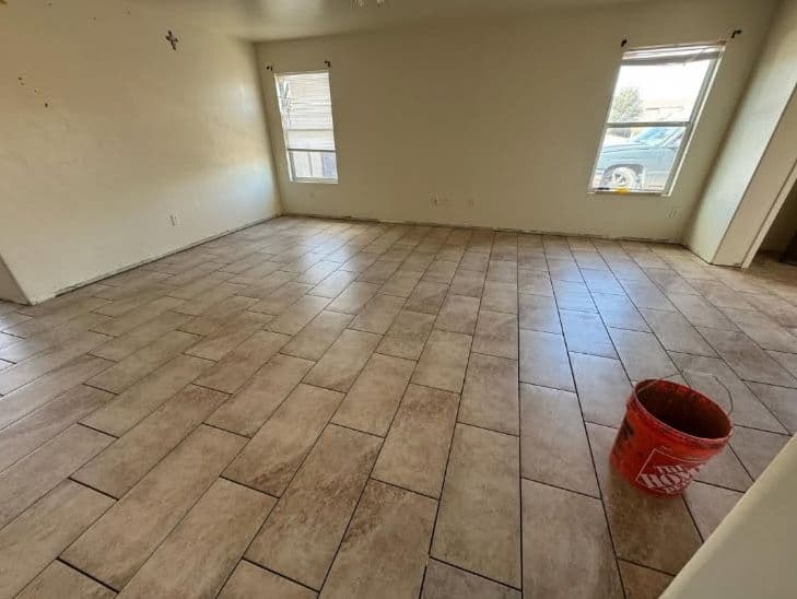 Spacious room with tiled floor, windows, and a Home Depot bucket in the corner.