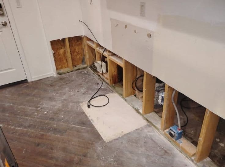 Home renovation progress showing exposed wall framing and flooring in a living space.