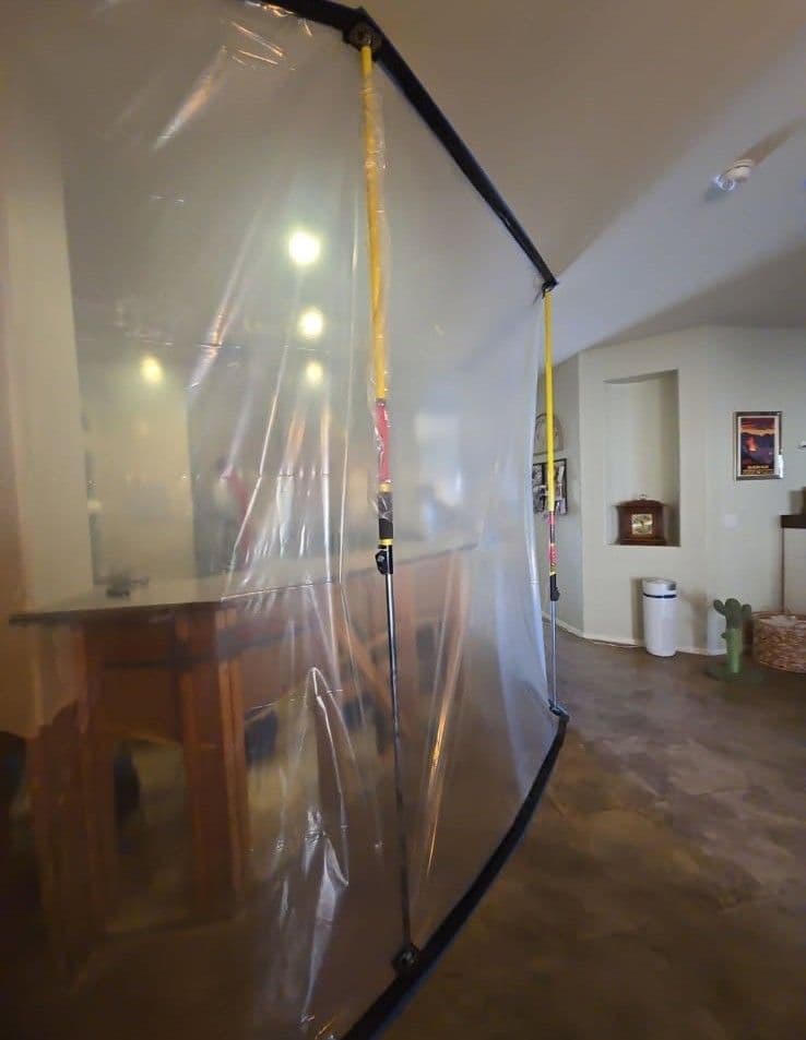 Plastic barrier in an indoor space, separating areas with yellow attachments and a wooden bar.